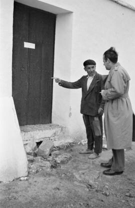 Barrio de El Palo. Investigador junto a vecino en la puerta de un caserón precintado. Reportaje para la revista El Caso. Diciembre de 1954. Málaga, España.